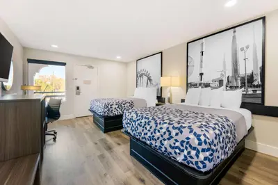 a hotel room with two beds and a desk at Super 8 by Wyndham Orlando Near Florida Mall in Orlando