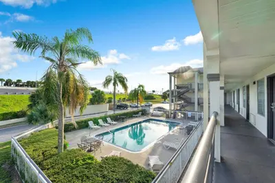 an apartment balcony with a pool and palm trees at Super 8 by Wyndham Orlando Near Florida Mall in Orlando