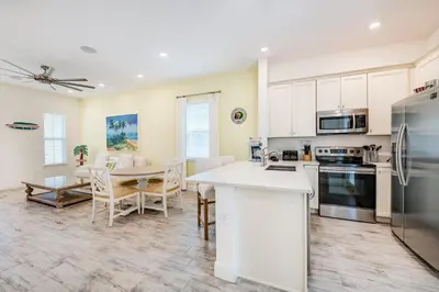 a kitchen with white cabinets and a table with chairs at Key Lime Cabana Cottage Near Disney With Margaritaville Resort & Island H2O Access - 3062Kl in Orlando