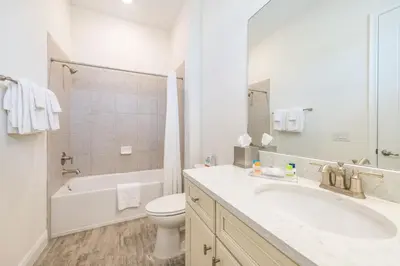 a white bathroom with a sink and a toilet at Playa Verde Cottage With Private Hot Tub Near Disney With Margaritaville Resort & Island H2O Access - 8028Dr in Orlando