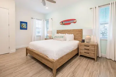 a bedroom with a large bed and a wooden dresser at Sun Baked Cottage With Hot Tub Near Disney With Margaritaville Resort & Island H2O Access - 8089Dr in Orlando