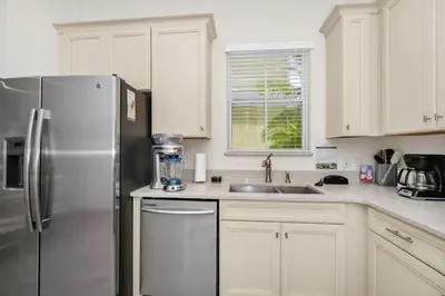 a kitchen with white cabinets and a stainless steel refrigerator at Teenie Bikini Cottage With Private Hot Tub Near Disney With Margaritaville Resort & Island H2O Access - 3071Kl in Orlando