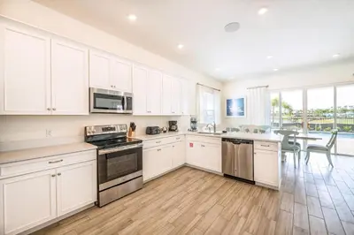 a kitchen with white cabinets and a dining room with a table at Bikini Bay Cottage With Private Pool Near Disney And Margaritaville Resort & Island H20 Waterpark Access - 3094Ph in Orlando