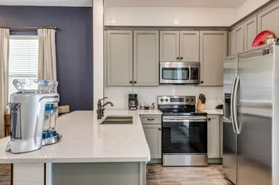 a kitchen with white cabinets and stainless steel appliances at Breezy Cottage With Hot Tub Near Disney With Margaritaville Resort & Island H2O Access - 8069Dr in Orlando
