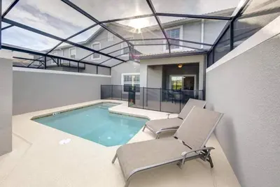 a house with a swimming pool and two chairs at Storey Lake 4b3b town home with private pool in Kissimmee