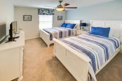 a bedroom with two beds and a flat screen tv at Storey Lake 4b3b town home with private pool in Kissimmee