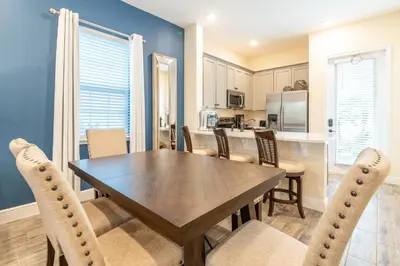 a dining room and kitchen with a wooden table and chairs at Nautical Cottage With Private Hot Tub Near Disney With Margaritaville Resort & Island H2O Access - 3044Sr in Orlando