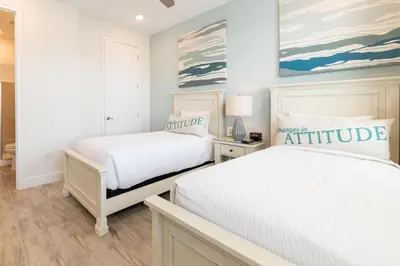 two beds in a bedroom with white walls and wood floors at Spacious Cottage With Private Pool Near Disney With Margaritaville Resort & Island H2O Access - 8009Su in Orlando