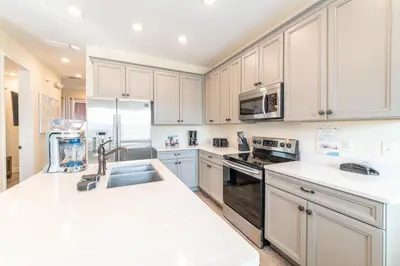 a kitchen with white cabinets and a sink at Fun In The Sun Cottage With Private Pool Near Disney With Margaritaville Resort & Island H2O Access - 8052Sh in Orlando