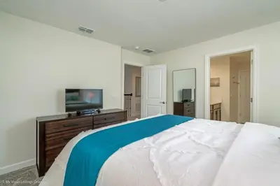 a bedroom with a large bed and a flat screen tv at 891Pbeach Amazing Champions Gate 8 Bedroom 5 Bed Villa in Orlando