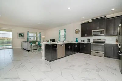 a large kitchen with black cabinets and a white tile floor at 891Pbeach Amazing Champions Gate 8 Bedroom 5 Bed Villa in Orlando