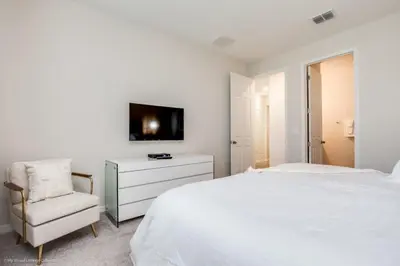 a white bedroom with a white bed and a chair at Solara Resort 9 Bedroom 6 Bathroom Resort Villa Villa in Orlando