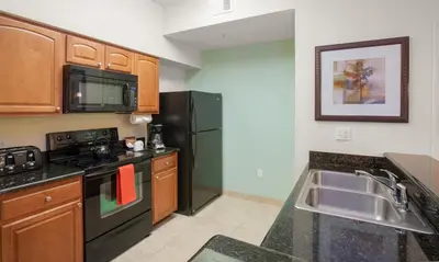 a kitchen with a sink and a black refrigerator at Lake Buena Vista Resort Village and Spa, Near Disney in Orlando