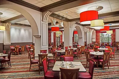 a dining room with tables and chairs and red chandeliers at Wyndham Lake Buena Vista – Disney Springs® Area in Orlando