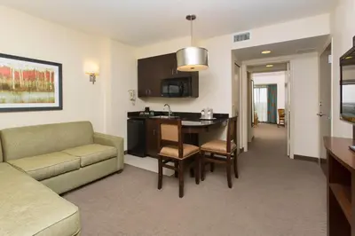 a living room with a couch and a table and a kitchen at Ramada Plaza by Wyndham Orlando Resort & Suites Intl Drive - Newly Renovated! in Orlando