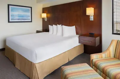 a hotel room with a large bed and two chairs at Ramada Plaza by Wyndham Orlando Resort & Suites Intl Drive - Newly Renovated! in Orlando