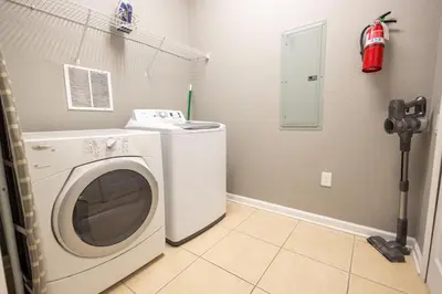 a laundry room with a washing machine and a fire extinguisher at DISNEY PARKS- International Dr - Orlando Luxury Condominium- Fully Equipped - 3bed & 2 bath- in Orlando
