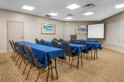 a conference room with blue tables and chairs and a white screen at Comfort Suites Maingate East in Orlando