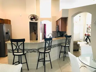 a kitchen with three bar stools and a counter at #503 Stunning 4 Bed, 3 bath villa with southwest facing pool and spa in Orlando