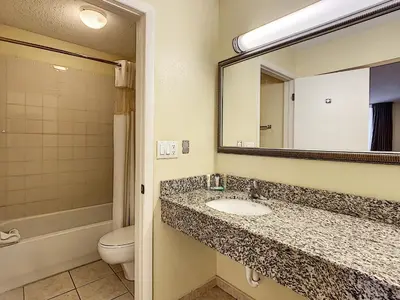 a bathroom with a sink and a toilet and a mirror at Stayable Orlando at Florida Mall in Orlando