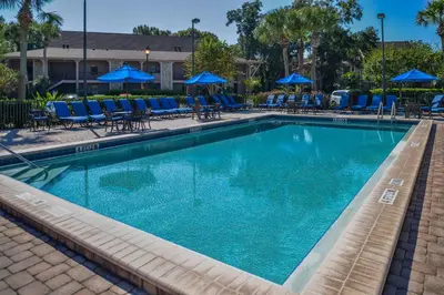 a large swimming pool with blue chairs and umbrellas at Hilton Vacation Club Polynesian Isles Kissimmee in Kissimmee