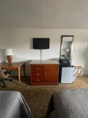 a hotel room with a television and a dresser with a mirror at Ambassador Inn in Kissimmee