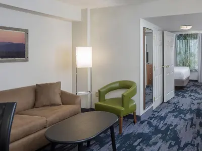 a living room with a couch and a green chair at Fairfield Inn & Suites by Marriott Orlando Lake Buena Vista in Orlando