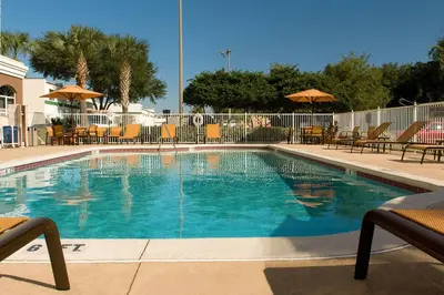 a swimming pool with blue water and chairs and umbrellas at Fairfield Inn & Suites by Marriott Orlando Lake Buena Vista in Orlando