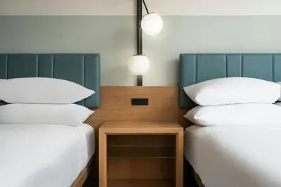 two beds with white pillows and a table between them at Sheraton Orlando Lake Buena Vista Resort in Orlando