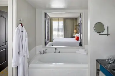 a white bathroom with a tub and a bedroom at Grand Bohemian Orlando, Autograph Collection in Orlando