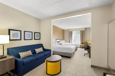 a hotel room with a bed and a blue couch at Comfort Suites Near Universal Orlando Resort in Orlando