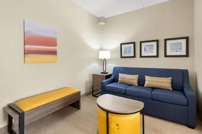 a living room with a blue couch and a stool at Comfort Suites Near Universal Orlando Resort in Orlando