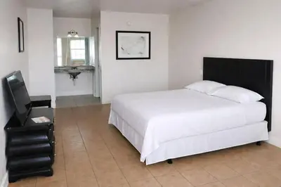 a bedroom with a large white bed and a sink at Siesta Motor Inn Kissimmee Near Disney World in Kissimmee