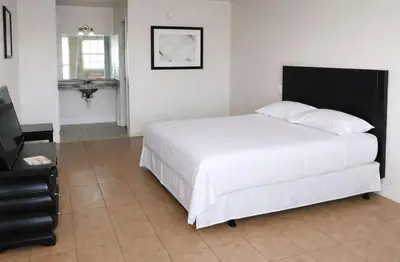 a bedroom with a large white bed with a black headboard at Siesta Motor Inn Kissimmee Near Disney World in Kissimmee