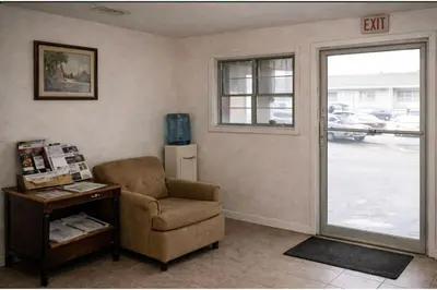 a living room with a chair and a sliding glass door at Siesta Motor Inn Kissimmee Near Disney World in Kissimmee