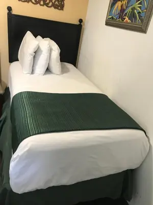 a bedroom with a bed with a green blanket and pillows at Hotel Belair Orlando Near Florida Mall in Orlando