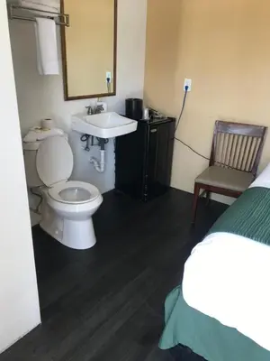a bathroom with a toilet and a sink and a bed at Hotel Belair Orlando Near Florida Mall in Orlando