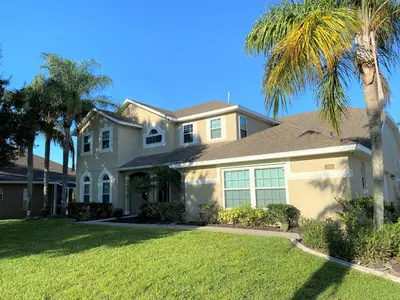 a house with palm trees in front of it at Mickeys Pearl - Phenomenal 7BR with 4 Master Suites Privacy Pool & Hot Tub Gas BBQ - 2 miles to Disney in Orlando