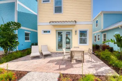 a patio with a table and chairs in front of a house at Sunrise Cottage Near Disney With Margaritaville Resort & Island H20 Waterpark Access - 2988Sr in Orlando