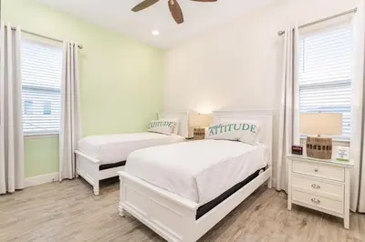 a white bedroom with two beds and two windows at Sunrise Cottage Near Disney With Margaritaville Resort & Island H20 Waterpark Access - 2988Sr in Orlando