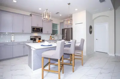 a kitchen with white cabinets and a table and chairs at Gorgeous 5 Bd Single Family Close to Disney @ Storey Lake Resort 2734 in Kissimmee