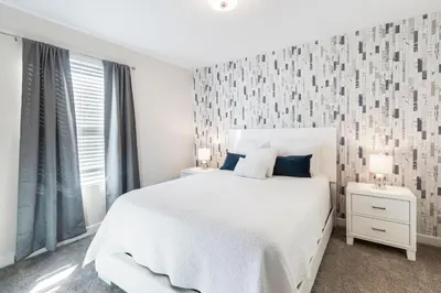 a white bedroom with a white bed and two lamps at 2957 FS - Luxury Oasis: 6BR Villa Pool Game in Kissimmee