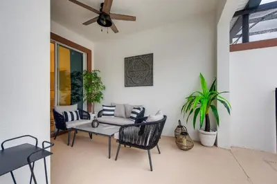 a patio with a table and chairs and a ceiling fan at 4808 LL Magical 4BR Disney Townhome Pool in Kissimmee