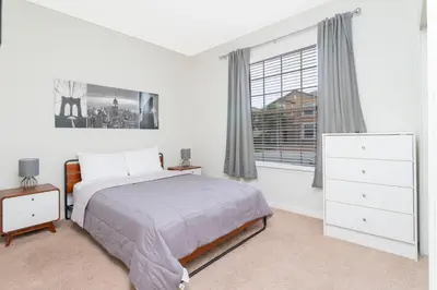 a white bedroom with a bed and a window at 8843 GC Windsor at Westside Luxury 5 BR Townhome in Kissimmee
