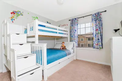 a bedroom with white bunk beds and a window at 8843 GC Windsor at Westside Luxury 5 BR Townhome in Kissimmee