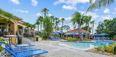 a resort pool with blue chairs and palm trees at 139PBD-SVH Lovely New Townhome! in Kissimmee