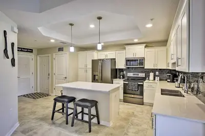 a kitchen with white cabinets and a island with two stools at Kissimmee Condo with Resort-Style Amenities! in Kissimmee