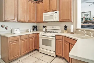 a kitchen with wooden cabinets and white appliances at 4 Mi to Disney Kissimmee Group Getaway in Orlando