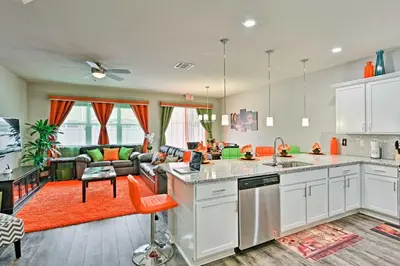 an open kitchen and living room with an orange couch at Theme Park Retreat with 5-Star Amenities - By Disney in Kissimmee