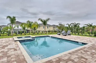 a swimming pool with two chairs and a house at 5 Mi to Disney Oasis with Pool and Patio in Orlando